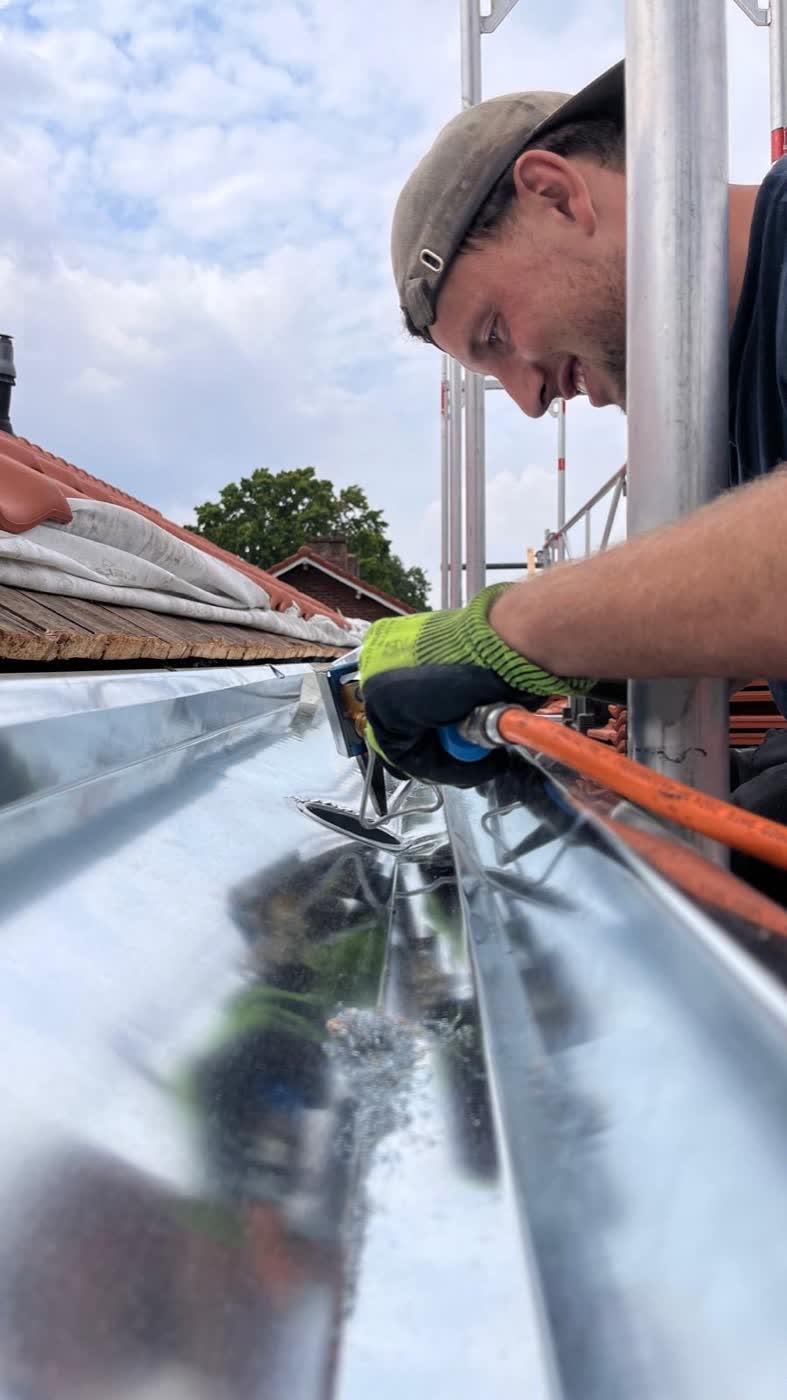 Vakman van Pannenbaas monteert een zinken dakgoot